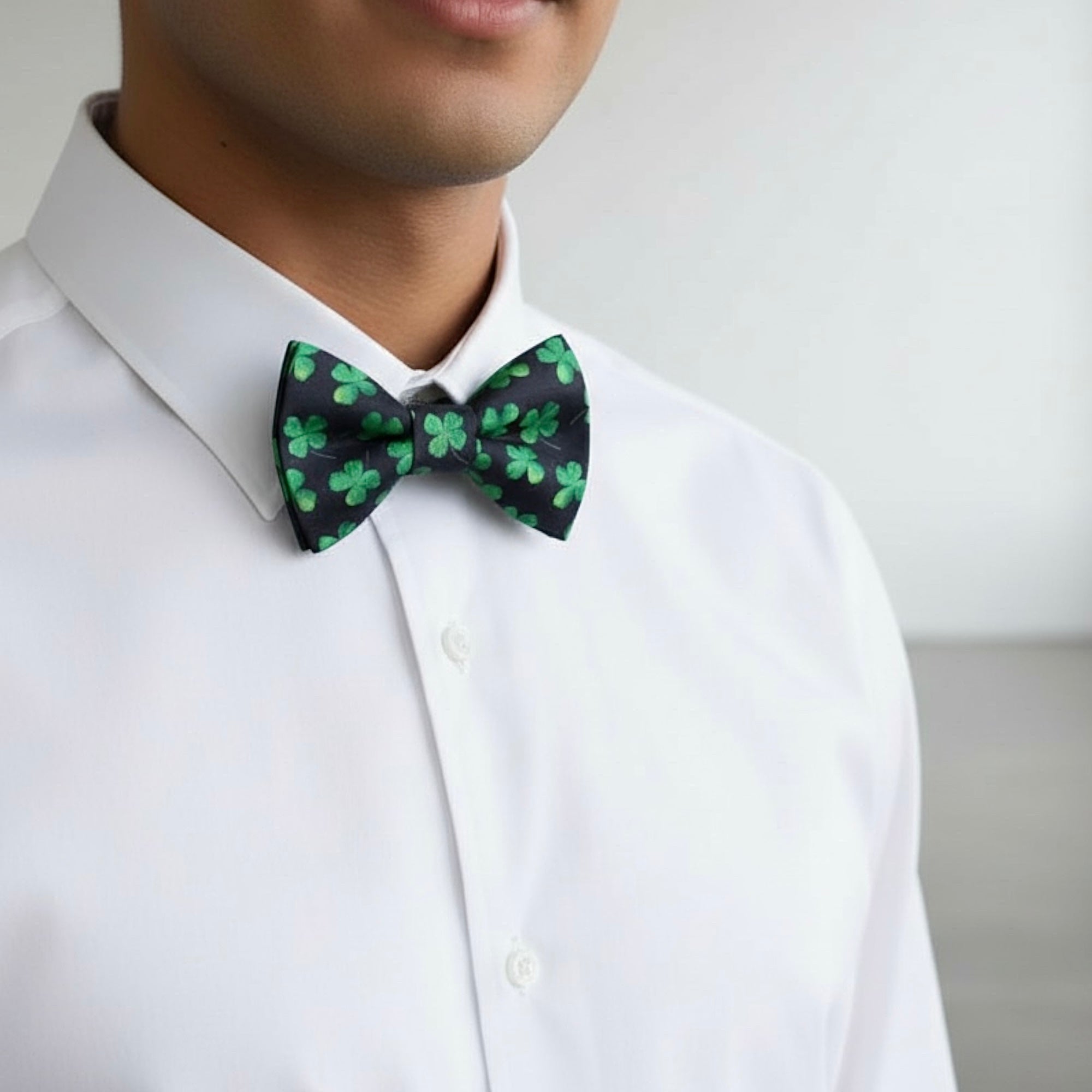 Person wearing a white shirt with a St. Patrick’s Day dog bow tie featuring green shamrock patterns.