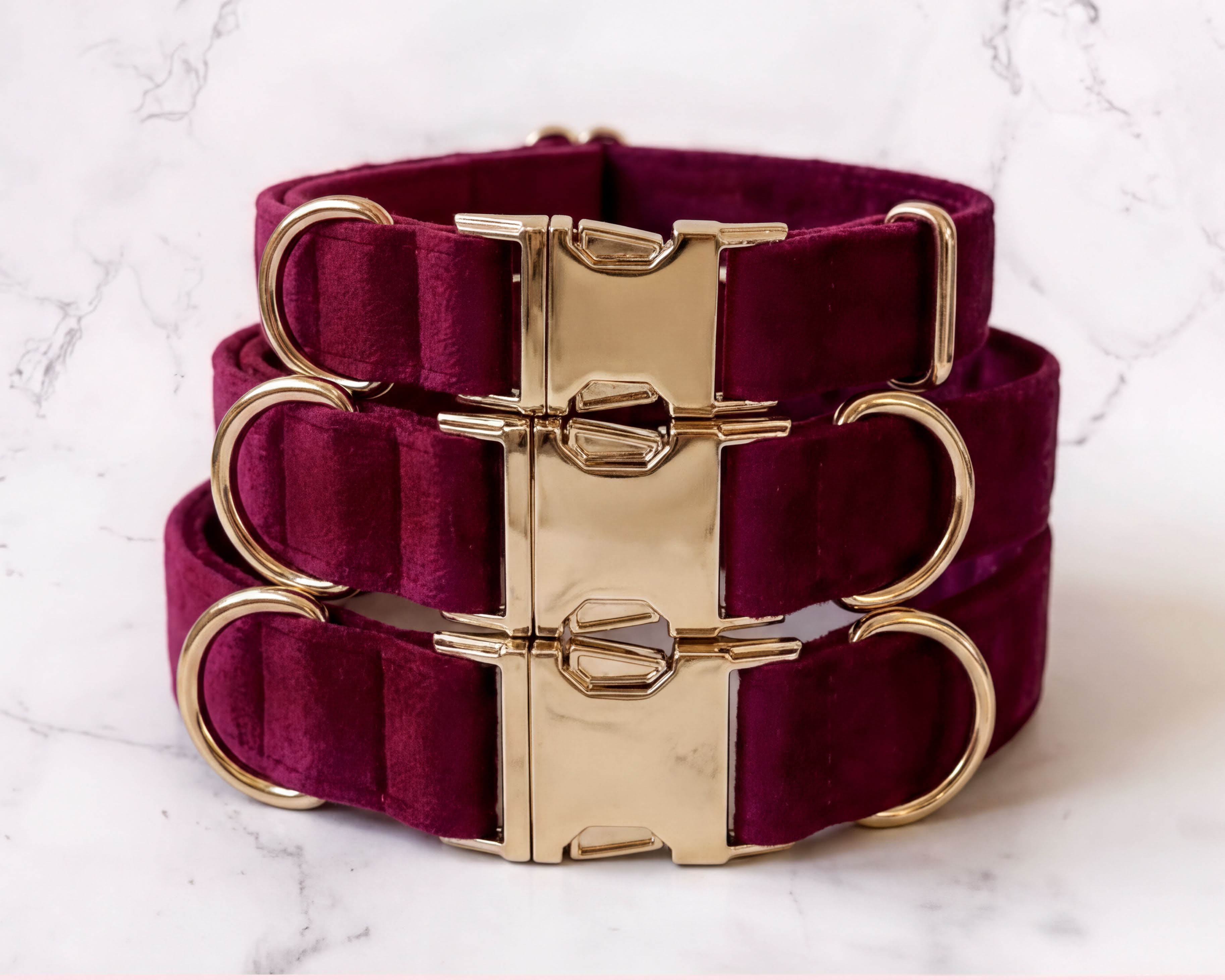 Burgundy dog collars with gold hardware on a marble background