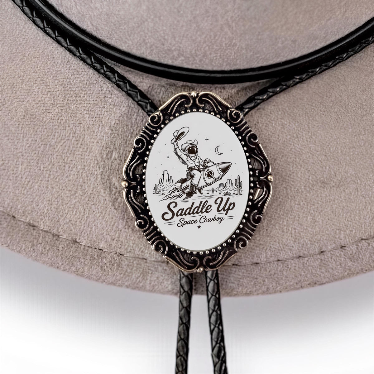 A close-up of a decorative metal buckle or badge with a cowboy illustration and the text "Saddle Up Space Cowboy" on it.
