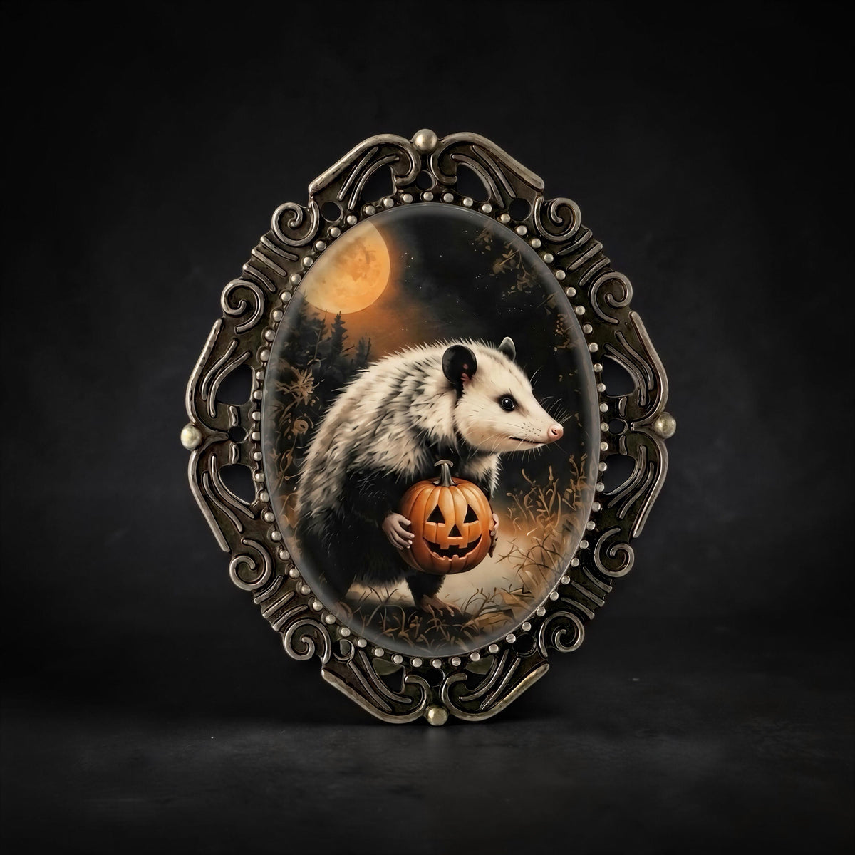 Halloween-themed oval brooch with a painted illustration of a small opossum holding a carved pumpkin.