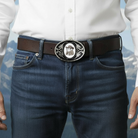 Person wearing a belt with a frog belt buckle against a mountainous background