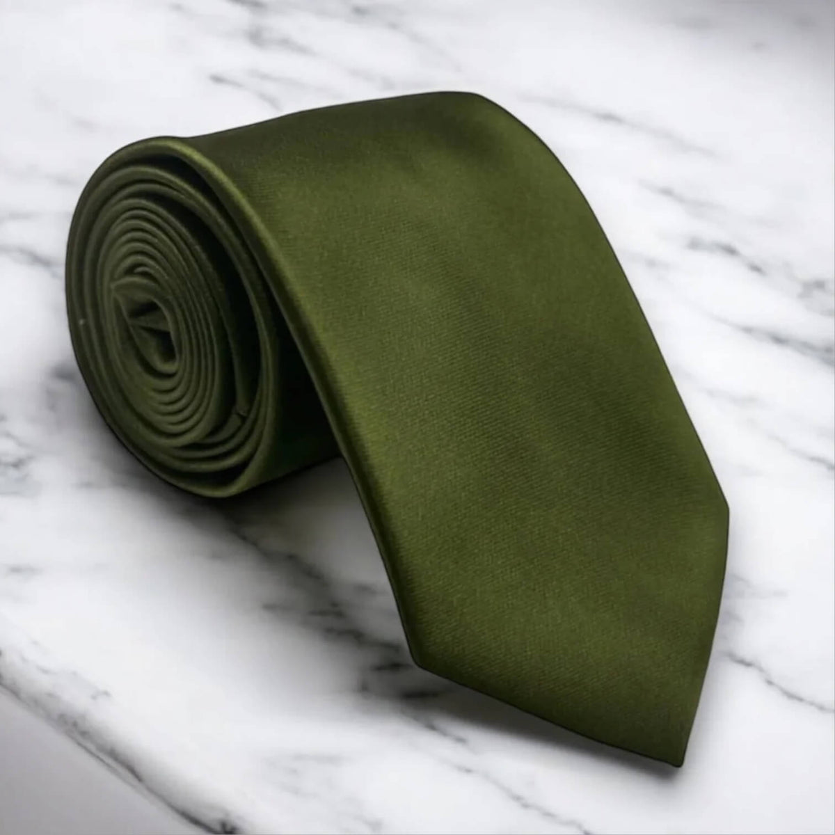 An olive green necktie, partially rolled and partially unrolled, displayed on a white marble surface with gray veining.