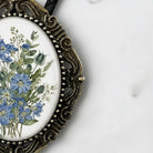 A decorative oval-shaped frame with a floral design on the inside, placed on a white surface.