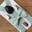 Sage green bowtie and sage green suspenders on a woven tray for a wedding by The Bold Bow Tie.