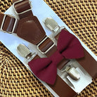 Brown suspenders with Cabernet bow tie on a woven surface