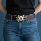 Person wearing blue jeans with a decorative frog belt buckle on a dark background