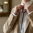 Floral bolo tie for men and women with leather cord worn by a groomsman in a wedding.