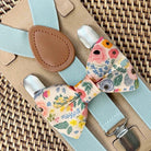 Floral bow tie for garden wedding and suspenders on a woven surface