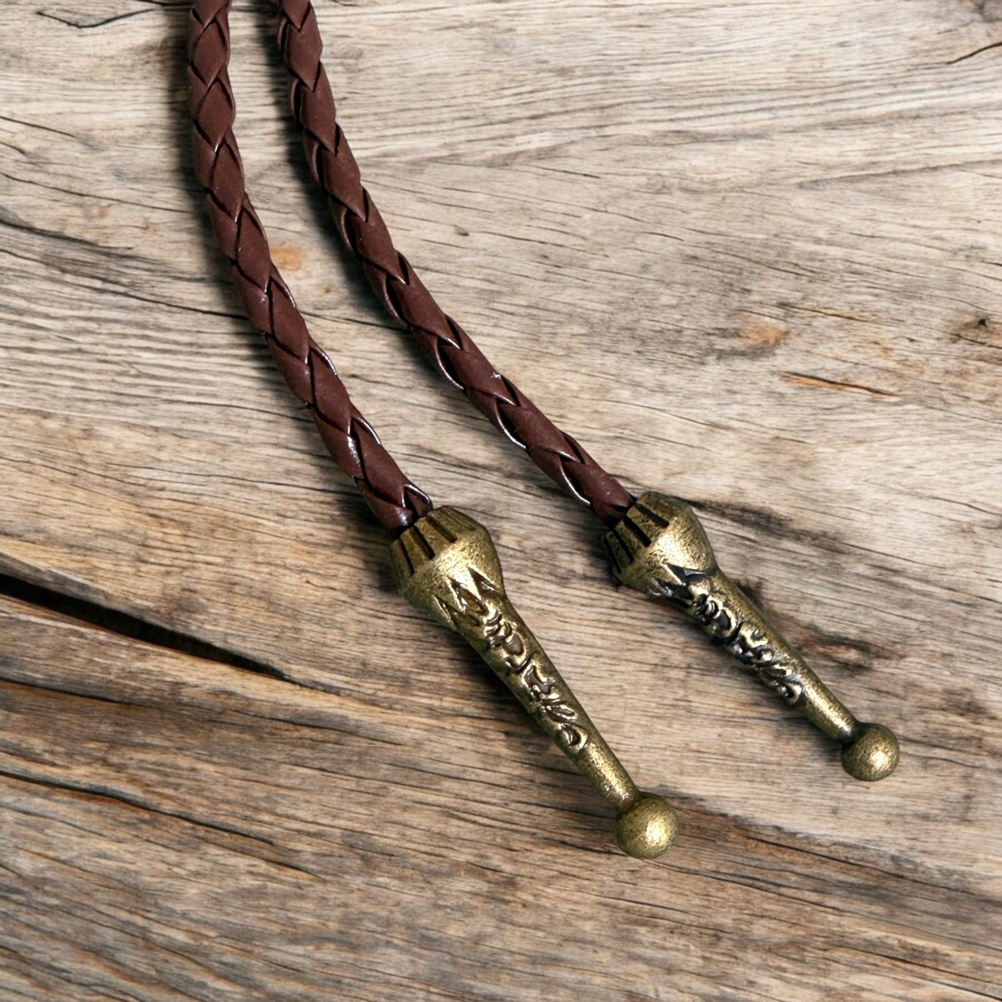 Braided leather bolo with brass ends on a wooden surface