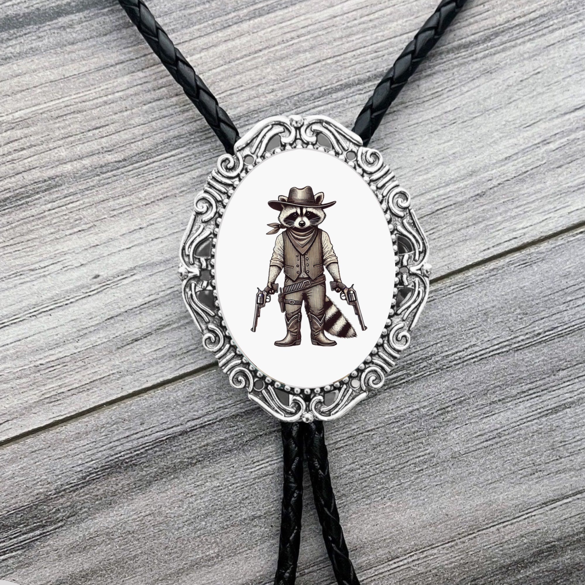 Bolo tie with raccoon wearing a hat and boots design on a wooden surface