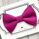 Hot pink dog bow tie on a white card with text on a wooden surface
