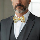 Man wearing a gray suit with a white shirt and a sunflower bow tie.