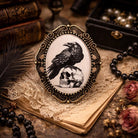 Vintage-style pendant with a raven and skull design on an old book with lace