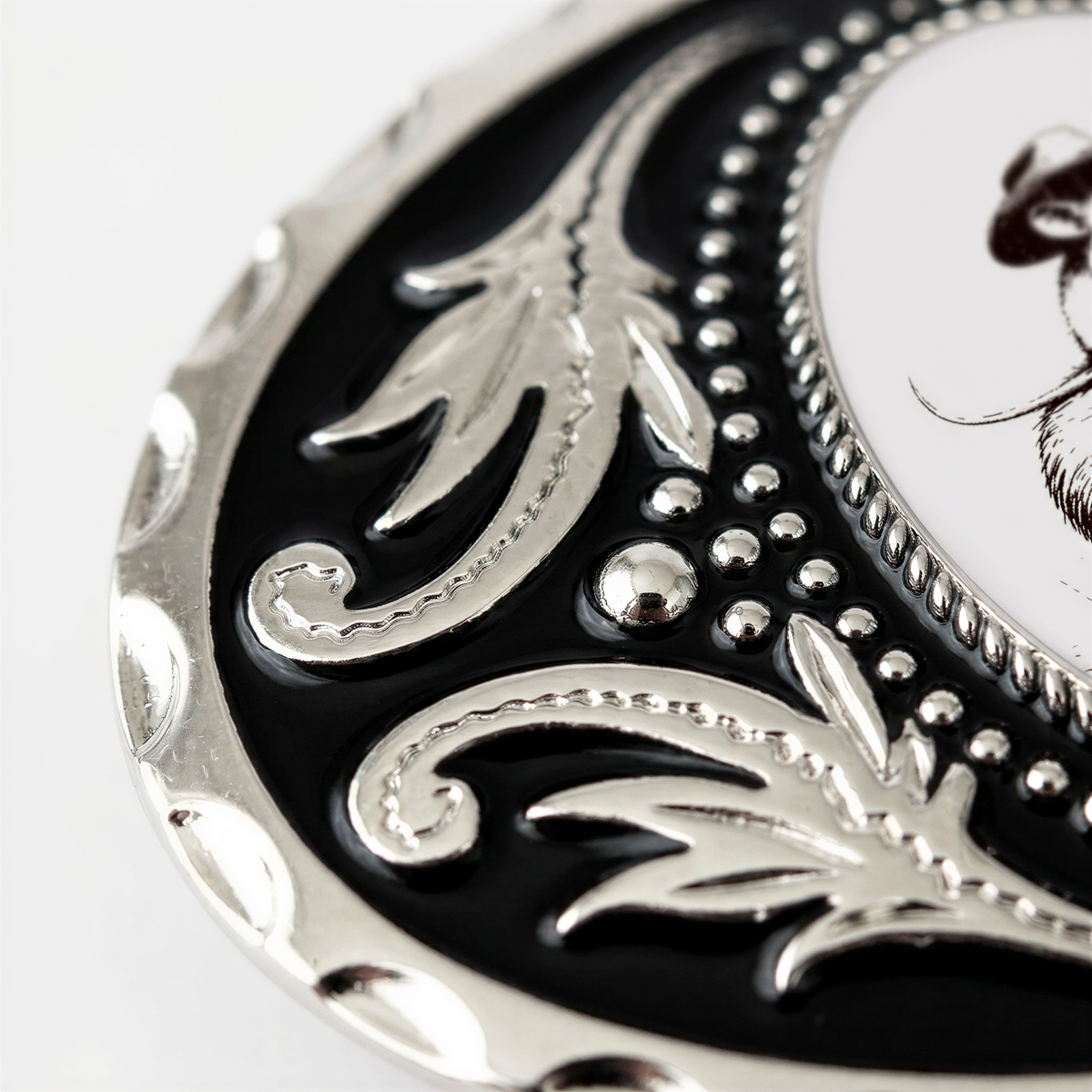 A close-up view of a decorative metal piece with a black and silver design, featuring intricate patterns and textures.