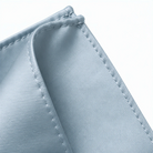 A close-up view of a light blue fabric, possibly a piece of clothing or a textile, with a slight curve and crease visible.