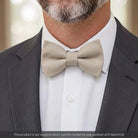 Tan bow tie for men worn by a man in a suit.