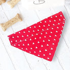 Red Valentines Day dog bandana with white hearts on a light wooden surface