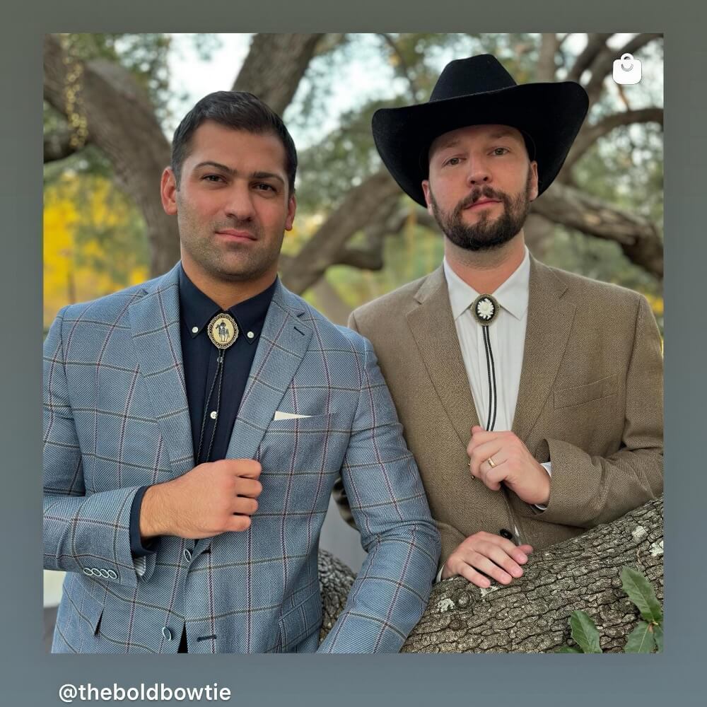 Two well-dressed men posing for a photo in an outdoor setting, with trees in the background.