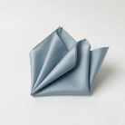 A folded light blue satin napkin is displayed against a white background.