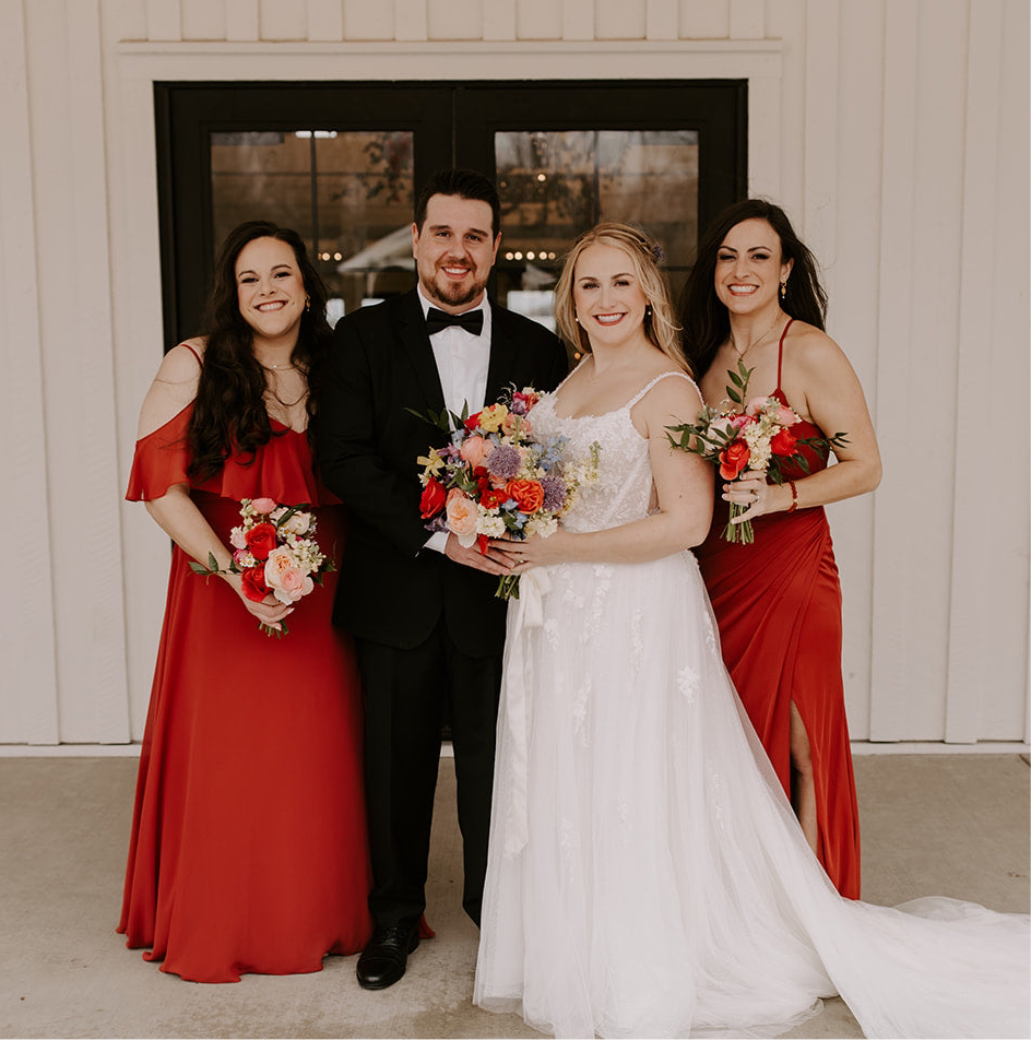 Satin black bow tie for weddings, groomsmen, and ring bearers being worn by groom with his bride and two bridesmaids.