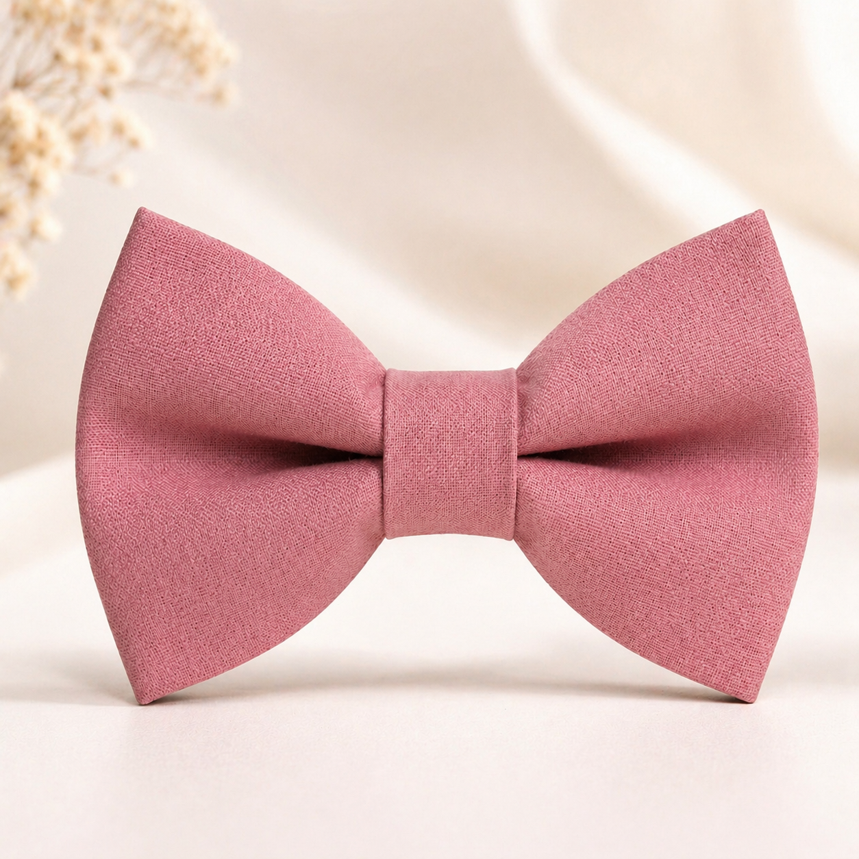 Blush pink dusty rose bow tie, formal wedding accessory for men, symmetrical pre-tied design on soft neutral background