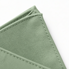 A close-up view of a green fabric, possibly a piece of clothing or a textile, with a slight crease visible.