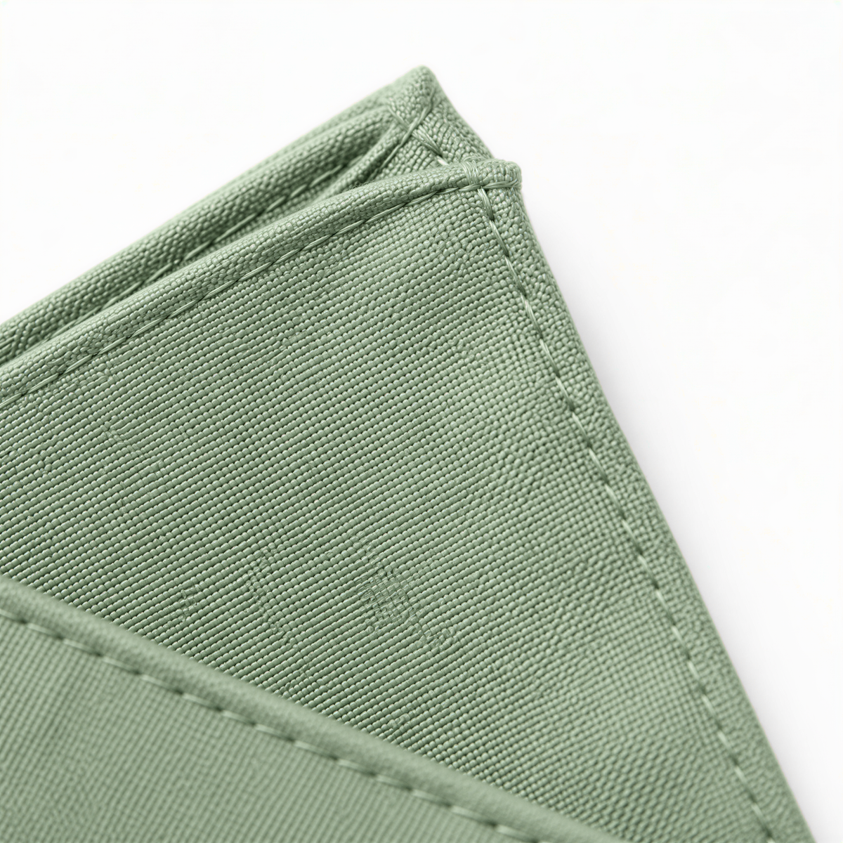 A close-up view of a green fabric, possibly a piece of clothing or a textile, with a slight crease visible.