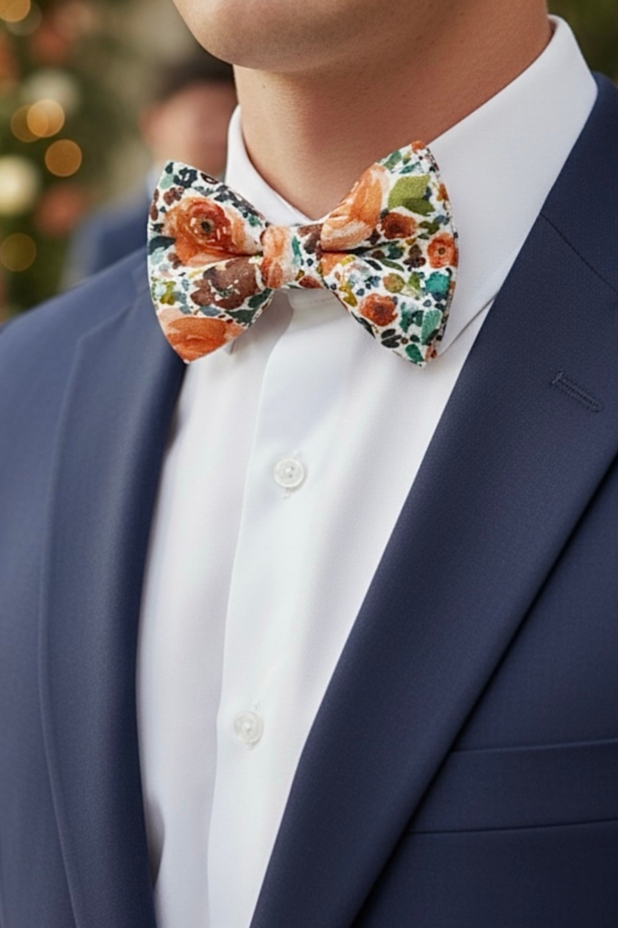 Groomsman wearing a sunset orange floral bow tie with a suit and white shirt.