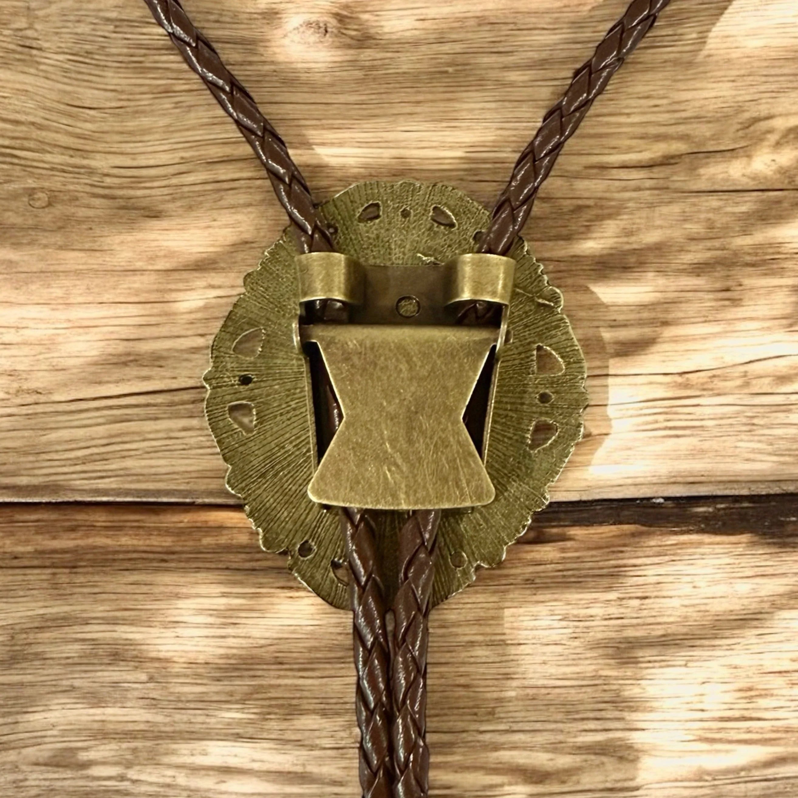 Back of bolo tie with bronze pendant and slider to adjust length on leather cord.
