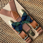 Brown suspenders with a Christmas plaid bow tie on a woven surface
