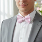 Man wearing a gray suit and pink Easter bow tie with a white shirt and pink striped bow tie.