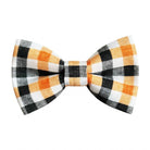 A Halloween plaid bow tie featuring a pattern of orange, black, white, and gray checkers on a solid white background.