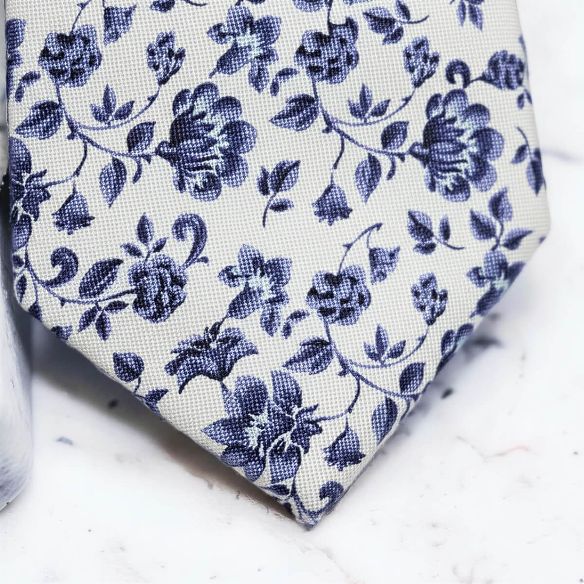 A close-up view of a blue floral tie with a floral pattern in shades of blue and white.