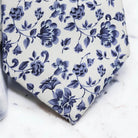 A close-up view of a blue floral tie with a floral pattern in shades of blue and white.