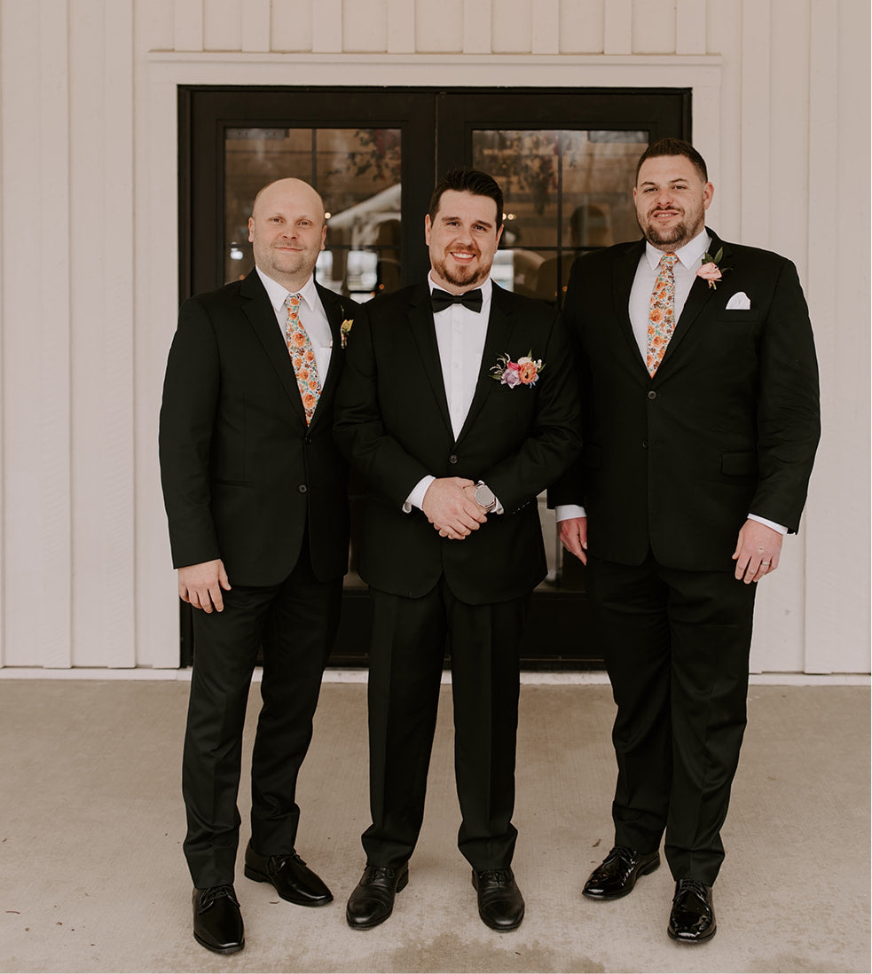 Groomsmen posing in burnt orange floral men’s ties for wedding.