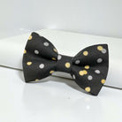 Black & Gold Confetti Bow Tie – Wedding & New Year’s Eve Formal Bow Tie for Grooms & Parties Leaning against a minimalistic white prop.