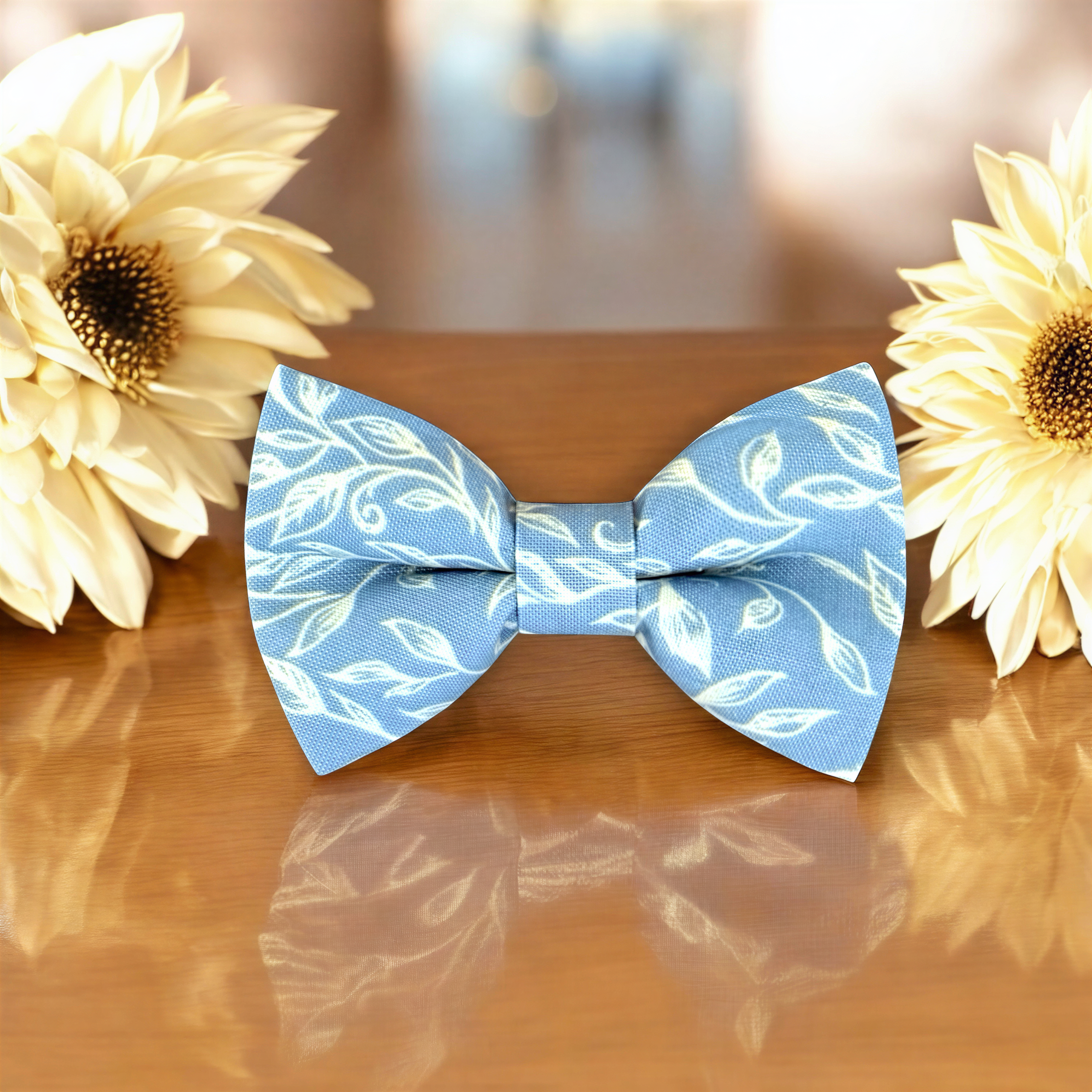 Blue & White Floral Bow Tie for groomsmen, wedding party and ring bearers surrounded by large flowers on wooden table.