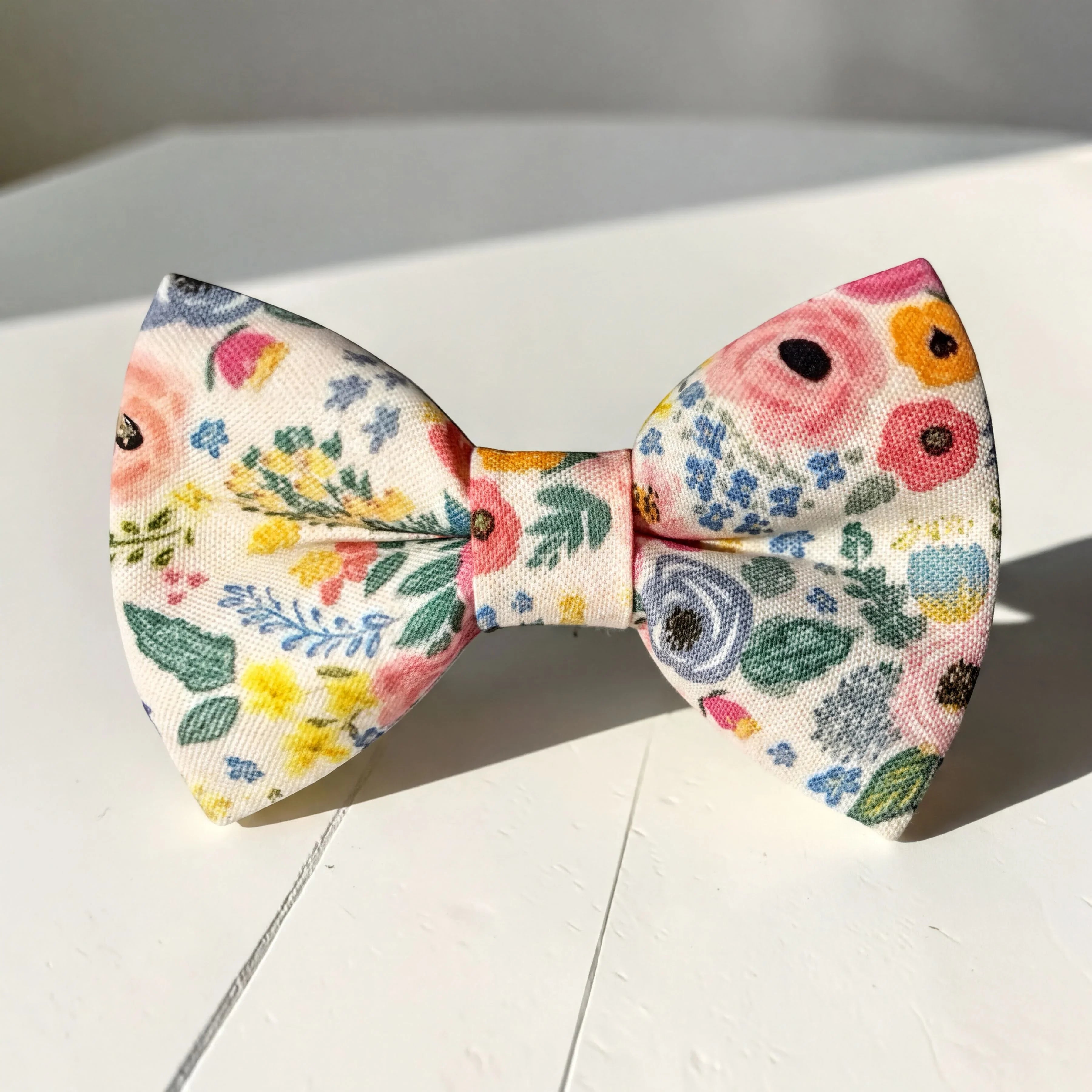 Floral bowtie for men, kids and babies on a white wooden table.