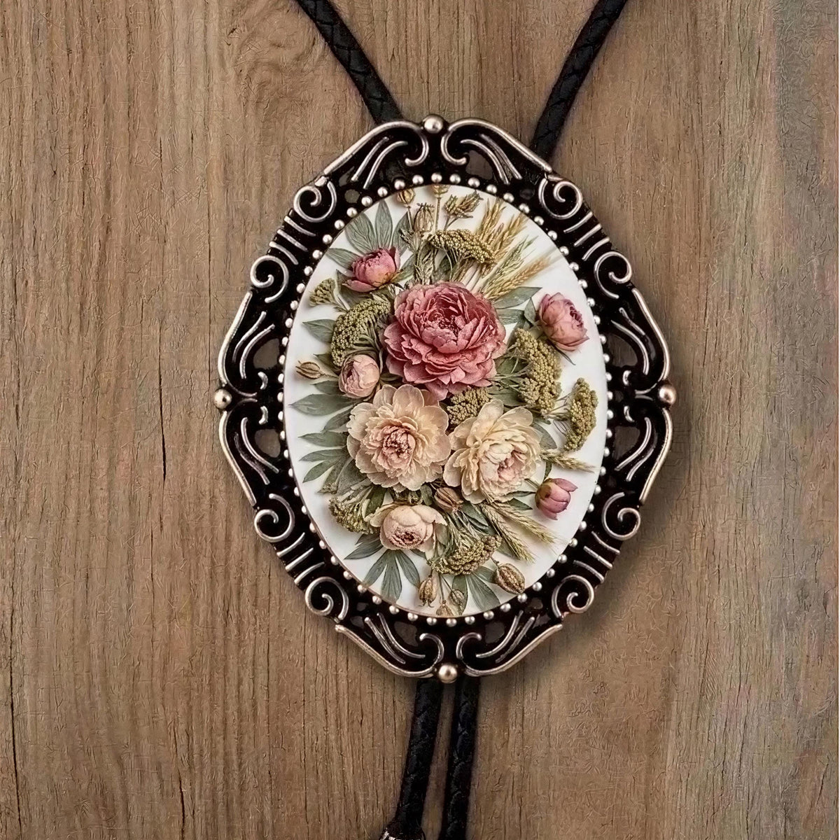 A decorative pendant featuring a floral design, including roses and other flowers, is displayed on a wooden surface.