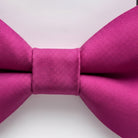 A close-up view of a vibrant pink bow tie against a plain white background.