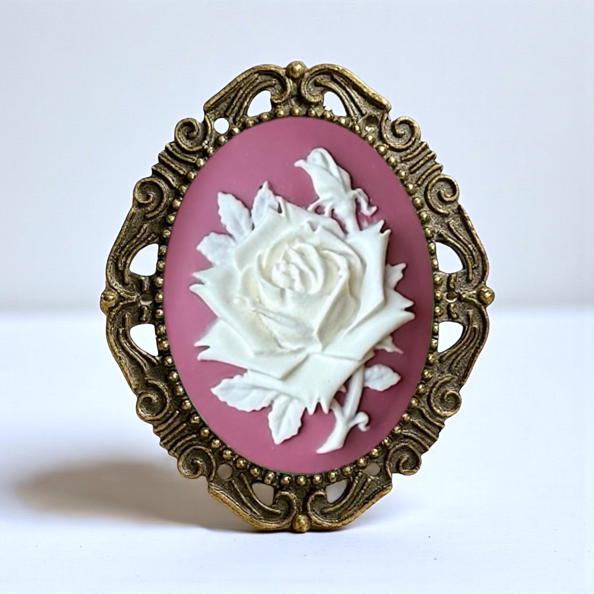 Cameo with white rose and gold frame on pink background