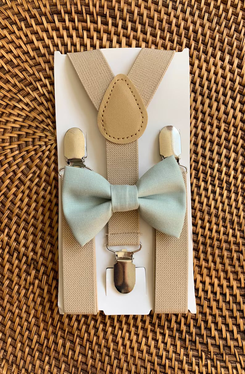 Sage Green Bow Tie & Tan Suspenders Set for wedding groomsmen, groom and ring bearers on a brown woven tray.