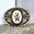 Decorative belt buckle with a cowboy opossum  design on a stone surface.