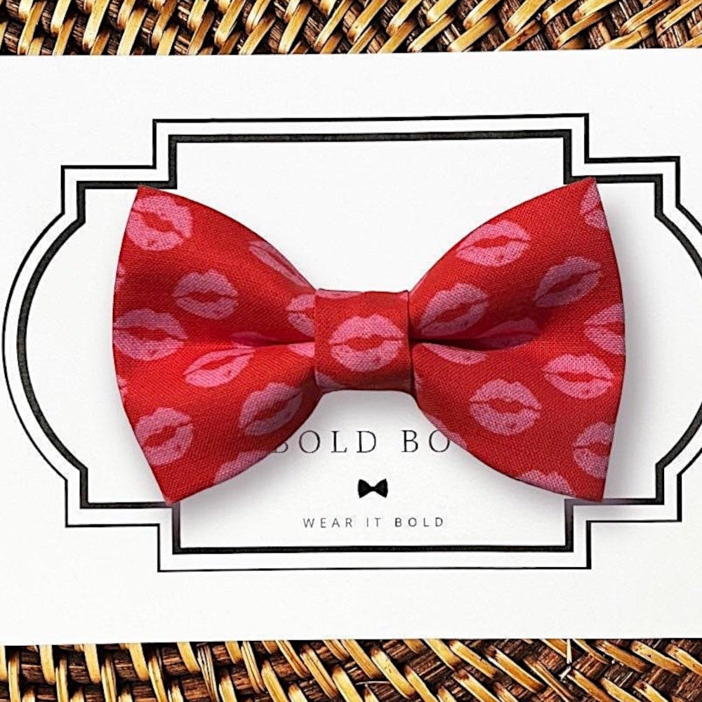 Red Valentines Day dog bow tie with pink lip prints on a white card with 'Wear It Bold' branding.