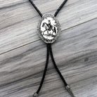 Bolo tie with a decorative pendant featuring a horse and rider on a wooden surface