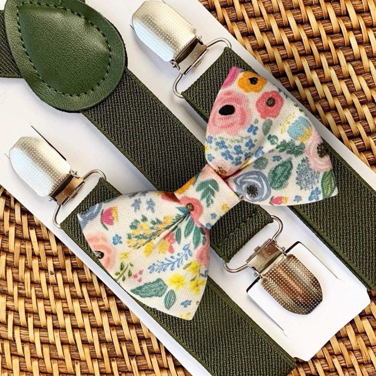 Floral bow tie and suspenders set for a wedding, groomsmen or ring bearer on a woven surface