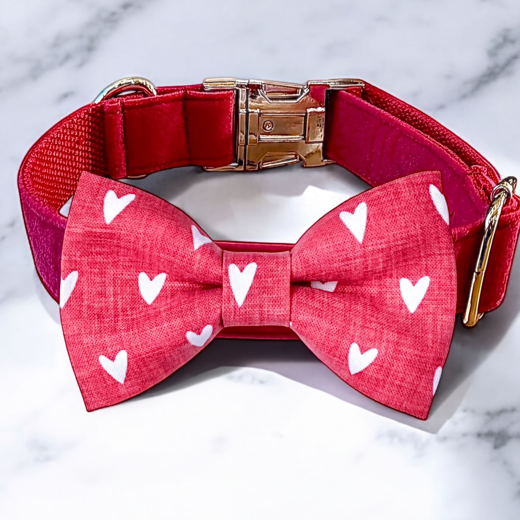 Close up of pink dog bow tie collar with white hearts and metal buckle
