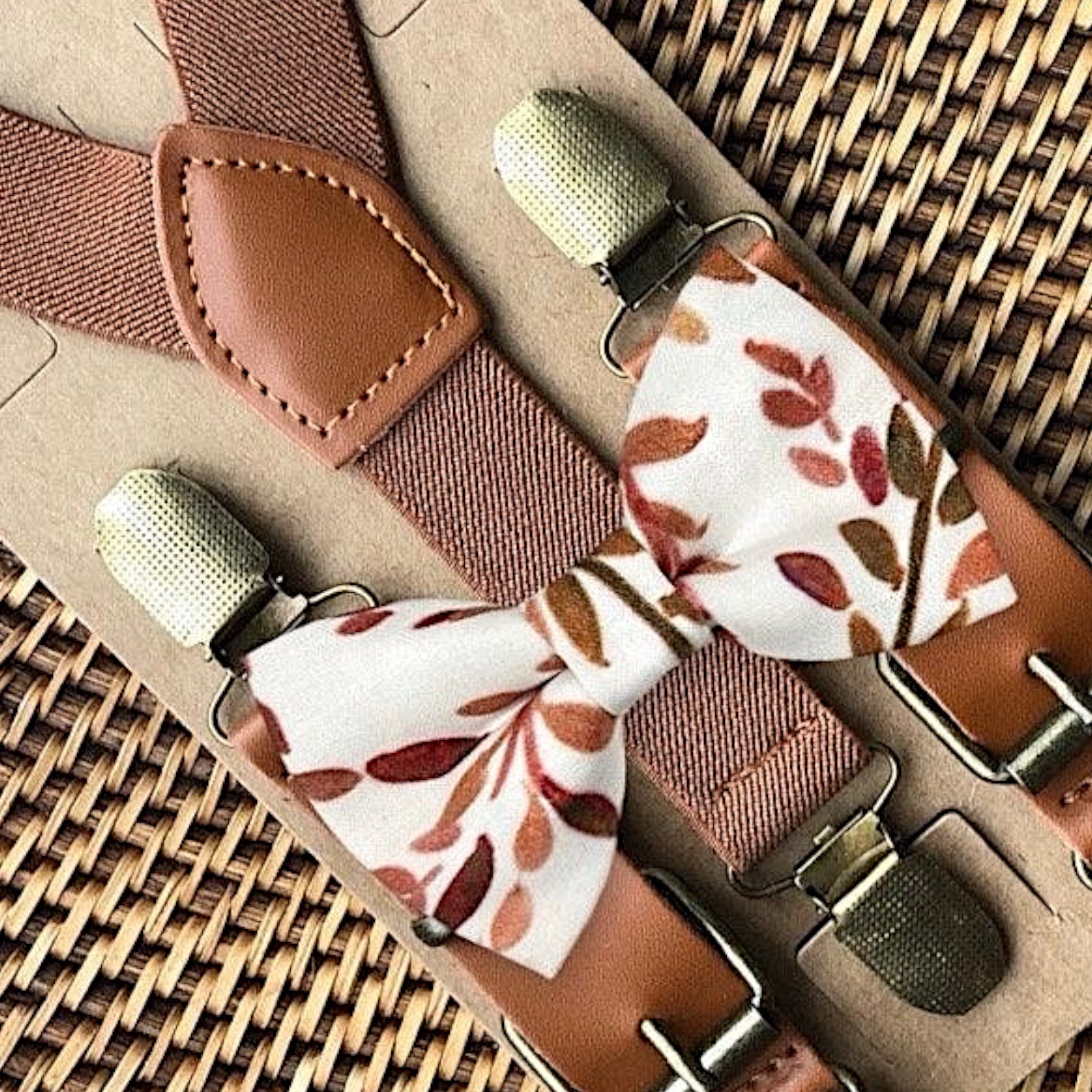 Brown suspenders with terracotta floral patterned clips on a woven surface