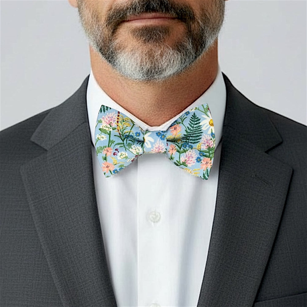 Size chart for pre-tied bow ties from The Bold Bow Tie detailing measurements across three sizes. Small is 3.5 inches wide and recommended for ages 6 months to 5 years. Medium is 4 inches wide and recommended for ages 6 to 12 years. Large is 4.5 inches wide and recommended for ages 13 years and up. Visual icons illustrate the relative sizes with horizontal arrows showing that width is measured from wingtip to wingtip. Bottom text notes that all bow ties are pre-tied and ready to add to your outfit.