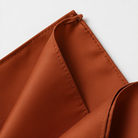 A close-up view of a folded orange fabric, possibly a napkin or tablecloth, with a slight crease visible.